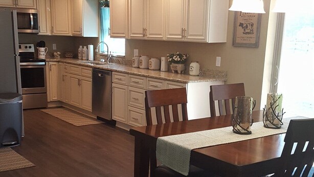 A spacious kitchen with white cabinets, a dining table, and a ceiling fan.