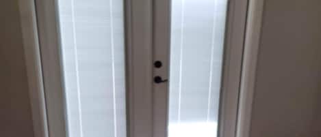 Une porte à deux battants avec des panneaux en verre dépoli et une poignée noire.