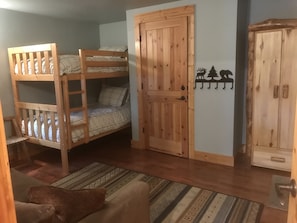 A bunk bed room with a wooden door, a wardrobe, and a patterned rug.
