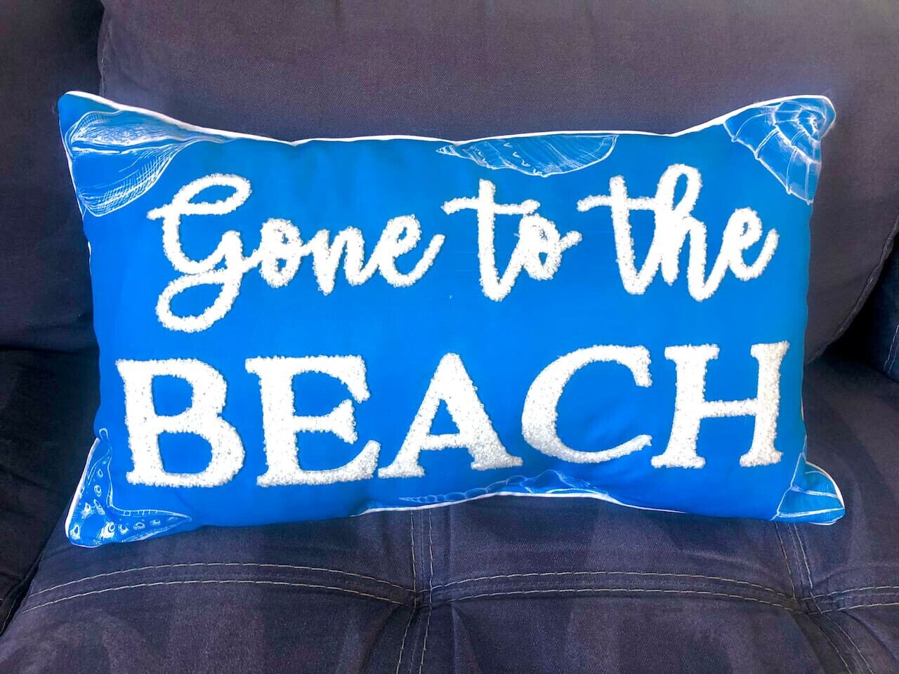 A blue pillow with white text that reads "Gone to the BEACH".