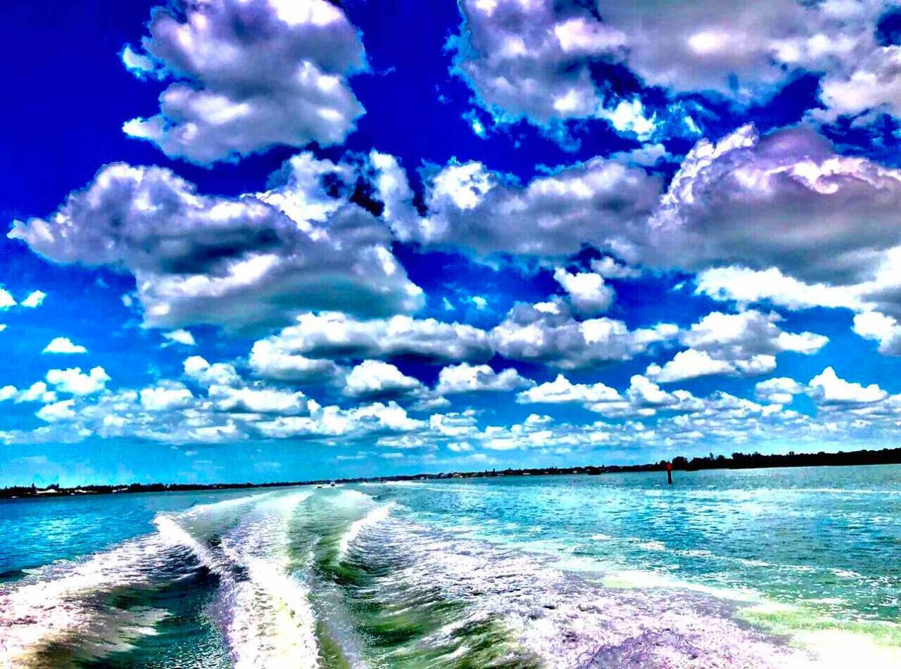 Ein klarer Himmel mit vereinzelten Wolken über einem Gewässer, wahrscheinlich ein Strand oder Küstenabschnitt.