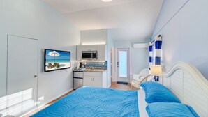 Une chambre avec un lit, une chaise, un bureau et une vue sur la cuisine.