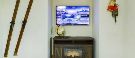 A living room with a flat-screen TV, a globe, and a fireplace.