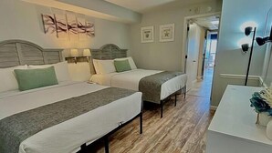 A hotel room with two beds, a desk, a mirror, and a door leading to another room. - Meticulous Oceanfront 1Bedroom Suite/ Jetted tub! (Myrtle Beach)