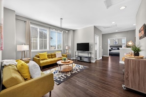 A modern living room with a sofa, TV, and a dining area.