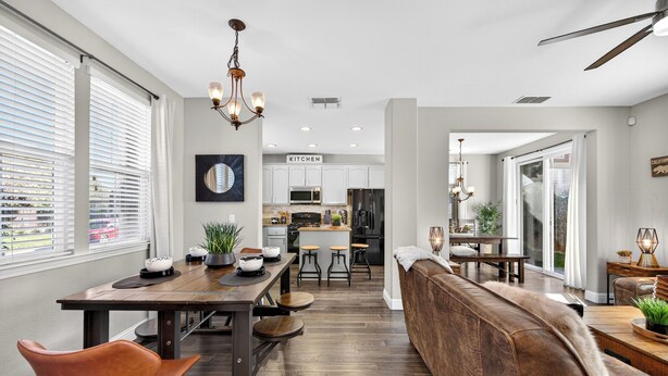 A modern kitchen with white cabinets, a central island, and a dining area with a wooden table and chairs.