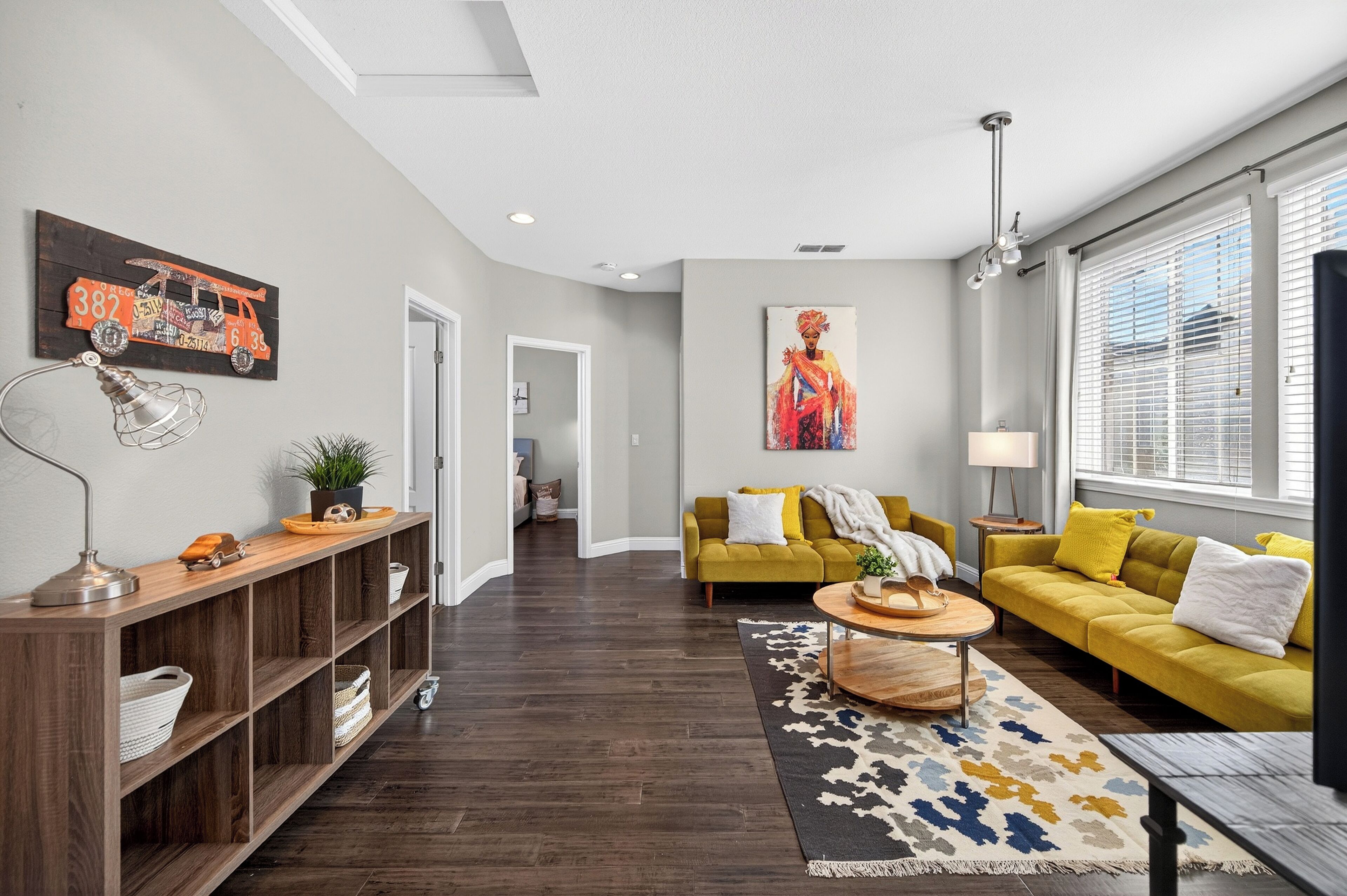 A modern living room with a sofa, a coffee table, a wooden console, and a painting on the wall.
