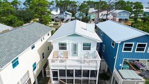Un quartier résidentiel situé sur la côte, composé de plusieurs maisons, dont une grande maison blanche dotée d’un balcon et une maison bleue avec une terrasse.