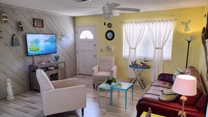 Un salon comprenant un téléviseur, un ventilateur de plafond, un canapé, une table basse et une lampe.