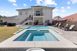 Piscina com uma casa de dois andares ao fundo.