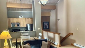 A living room with a black leather sofa, a dining table, and a kitchen in the background. - In Town Vacation Rental within Walking Distance to Slopes, Bike Trails & Main St (Breckenridge)