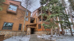 A multi-story wooden building with a stone foundation, a stone pillar, and a snow-covered ground. - In Town Vacation Rental within Walking Distance to Slopes, Bike Trails & Main St (Breckenridge)