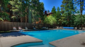 A swimming pool with lounge chairs and a wooden fence. - In Town Vacation Rental within Walking Distance to Slopes, Bike Trails & Main St (Breckenridge)