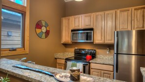 A kitchen with wooden cabinets, a stainless steel refrigerator, a microwave, and a stove. - In Town Vacation Rental within Walking Distance to Slopes, Bike Trails & Main St (Breckenridge)