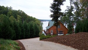 A wooden cabin with a dock, surrounded by dense forest and a body of water in the background. - Log Cabin On Lake Keowee-Big Lake Mountain Views (Six Mile)