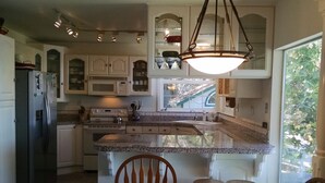 A kitchen with white cabinets, a granite countertop, a built-in stove, and a hanging light fixture.