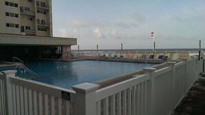 A swimming pool with a white fence, a lifeguard stand, and a flag.