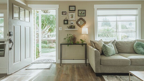 A living room with a sofa, a coffee table, a door leading outside, and a wall with framed pictures. - Contemporary Boutique Bungalow+Backyard+Walkable (San Luis Obispo)