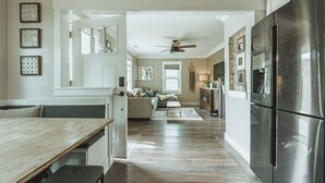 A modern kitchen with a stainless steel refrigerator, wooden dining table, and a ceiling fan. - Contemporary Boutique Bungalow+Backyard+Walkable (San Luis Obispo)