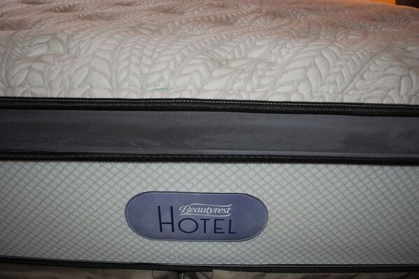 A close-up of a hotel bed with a quilted headboard and a tag labeled "Beautyrest HOTEL".