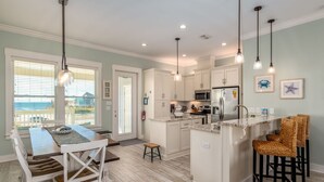 A modern kitchen with white cabinetry, a central island, and pendant lighting.