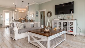 A living room with a sofa, coffee table, and a TV mounted on the wall.