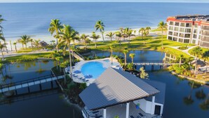 A resort with a pool, lounge chairs, and a view of the ocean.
