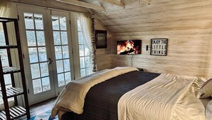 Een gezellige slaapkamer met een groot bed, een televisie en een motiverende quote op de muur.