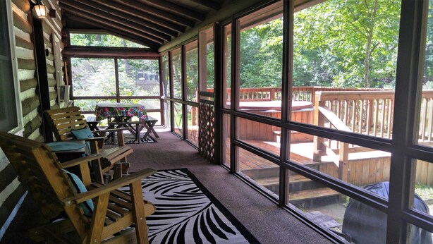 Un porche cubierto con muebles de madera y ventanas amplias que dan a una terraza.