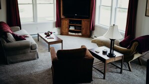 A living room with a sofa, armchair, coffee table, lamp, and entertainment center.