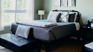 A bedroom with a bed, a nightstand, a lamp, and a ceiling fan.