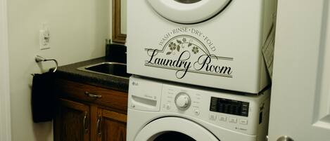 A laundry room with stacked washers and dryers, wooden cabinets, and a beige rug.