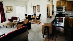 A spacious living area with a dining table, a sofa, and a kitchen with wooden cabinets and modern appliances.