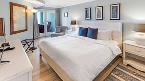 Une chambre d’hôtel avec un grand lit, un bureau, une chaise, un ventilateur de plafond et une vue sur l’extérieur.