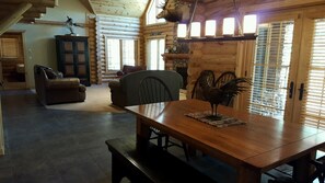 Cozy cabin interior with a large dining table, comfortable seating area, and a fireplace.