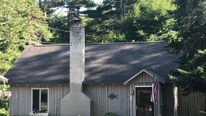 A small wooden building with a chimney, a door with an American flag, and a window. - Cabin in village of Suttons Bay! (Suttons Bay)