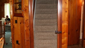 A wooden staircase with a carpeted landing. - Cabin in village of Suttons Bay! (Suttons Bay)