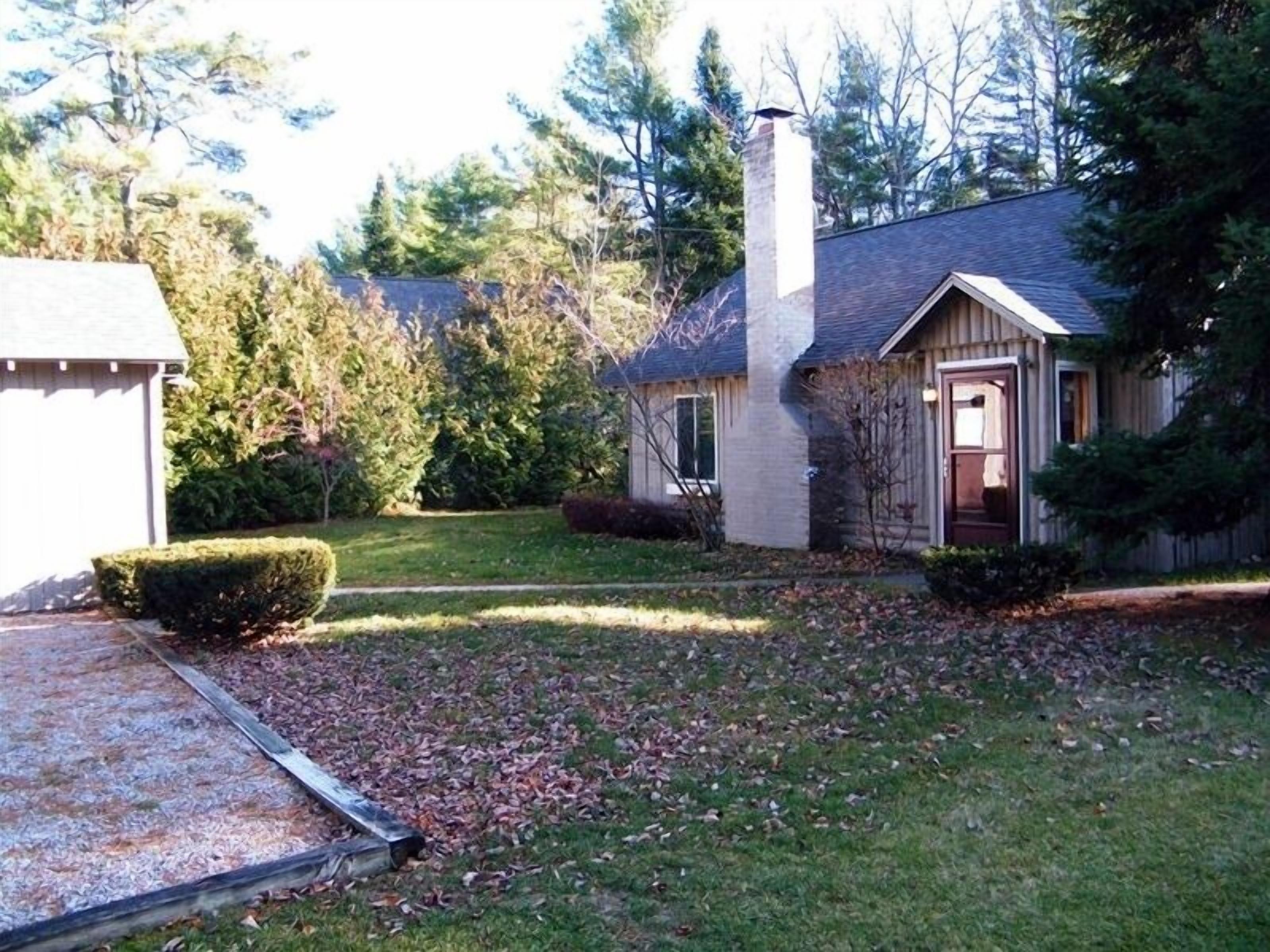 A single-story house with a chimney, a garage, and a well-maintained lawn.