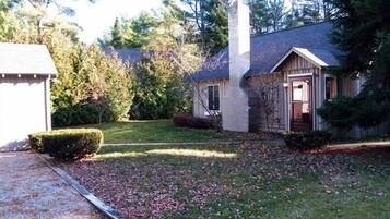 A single-story house with a chimney, a garage, and a well-maintained lawn.
