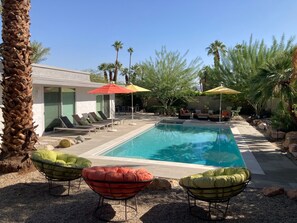 A poolside area with lounge chairs, umbrellas, and a pool.