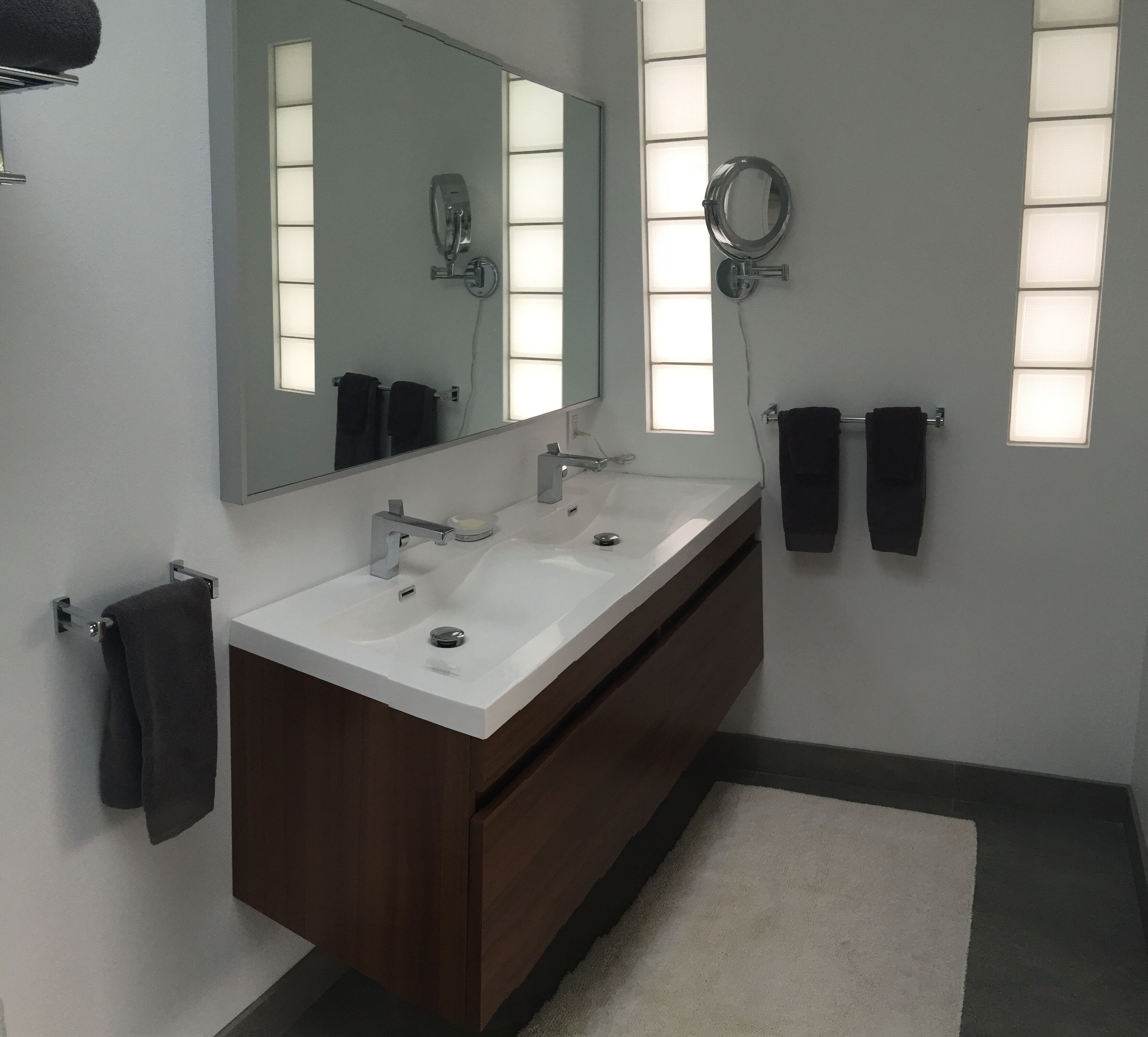 Un bagno moderno con un mobile bagno doppio, uno specchio grande e due portasciugamani.