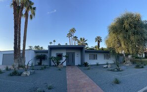 A modern two-story house with a paved driveway leading to the entrance.