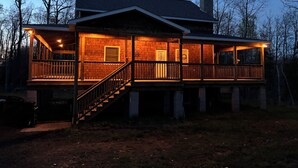 A two-story house with a wooden deck and a staircase leading to the upper level. - Six bedroom home with a hot tub, pool and an outdoor bar on a two acre lot. (Marquette)