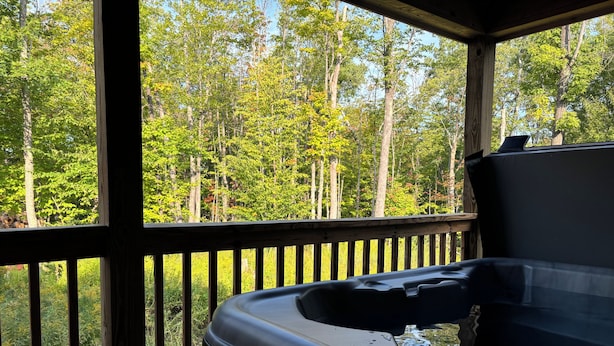 A hot tub on a wooden deck with a view of a forest. - Six bedroom home with a hot tub, pool and an outdoor bar on a two acre lot. (Marquette)