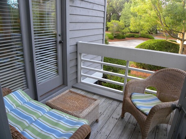 A balcony with wicker furniture and a view of a landscaped garden. - Great Rates! Screen Porch! Pool Just Steps Away! (Seabrook Island)