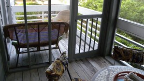 A covered porch with a wicker chair and a small table. - Great Rates!  Screen Porch!  Pool Just Steps Away! (Seabrook Island)