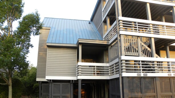 A modern multi-story building with a flat roof, large windows, and a covered entrance area. - Great Rates!  Screen Porch!  Pool Just Steps Away! (Seabrook Island)