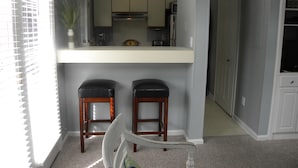 A compact kitchen with a white countertop, two wooden barstools, and a potted plant. - Great Rates!  Screen Porch!  Pool Just Steps Away! (Seabrook Island)