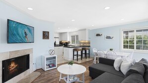 A modern living room with a fireplace, a dining area, and a kitchen. - Air Conditioning! Cottage 2-blocks from Beach (Newport Beach)