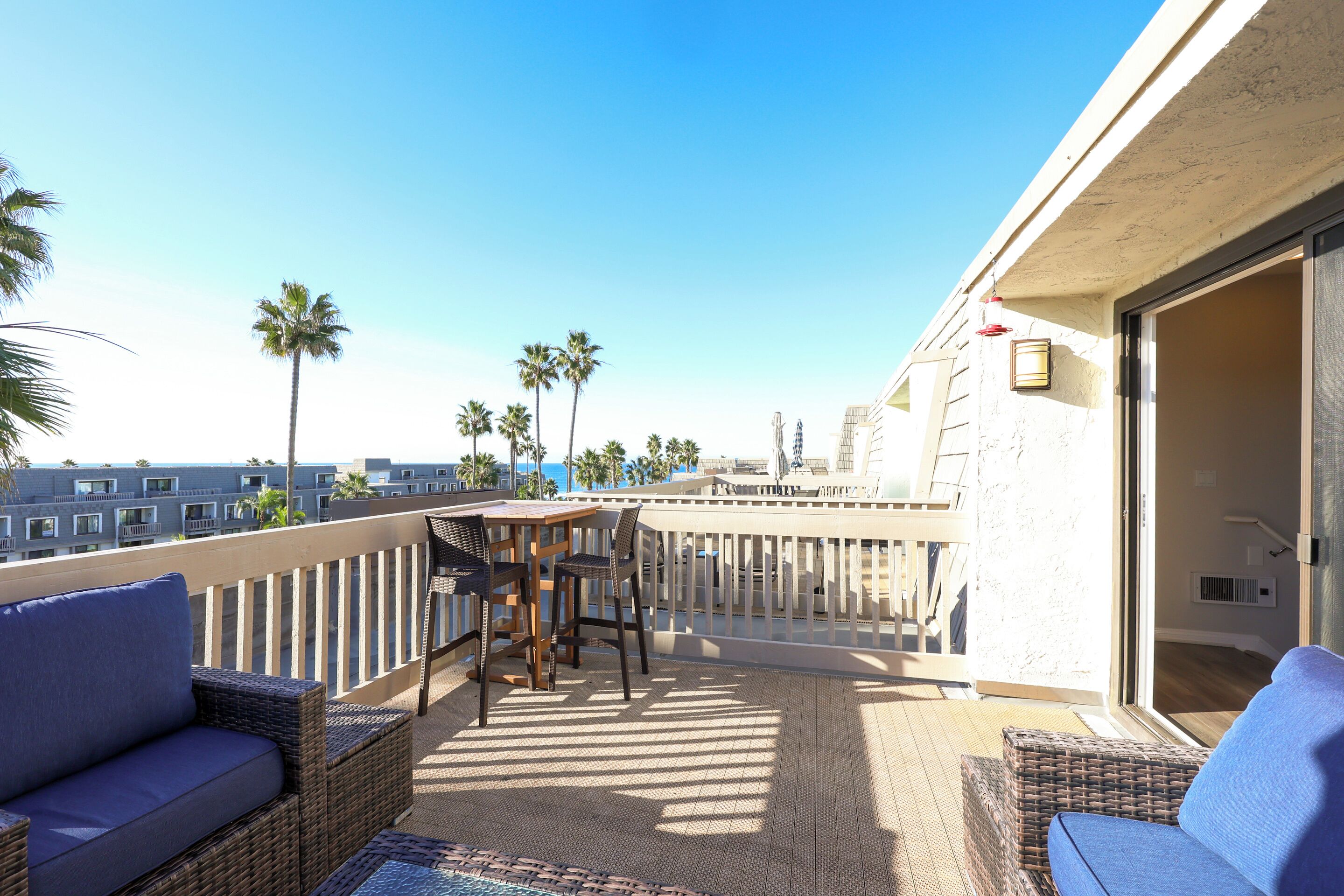 A balcony with wicker furniture, a table, and chairs.